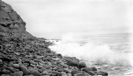 Waves on basalt cobbles (three feet long) at Colnett Bay with conglomerate cliffs in background, facing southwest