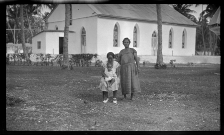 Cook Islands women and infant with church in background