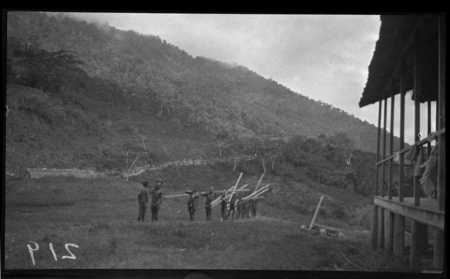 Men carrying wood beams at Popole, a Catholic mission in the mountains of Central Province