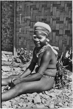 Adolescent girl, Kena, with talcum powder around her eyes, and marsupial fur cap, smiling while sitting near Cooks&#39; Kwiop ...