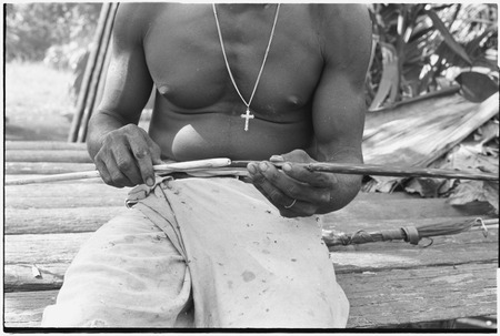 Ambaiat: arrow hafting, tip is attached to shaft with plant fibre by man wearing cross necklace