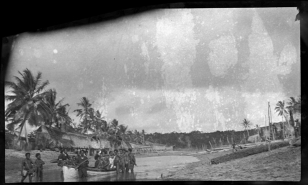 Men in and around a boat, with Baimuru (Vaimuru) village in background, Gulf Province