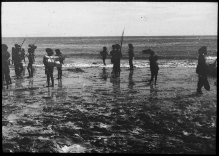 People gathered at the shore, many are carrying objects