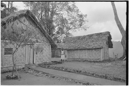 Edwin Cook&#39;s house in Kwiop: house and kitchen structure, employee stands between