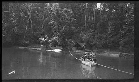 Men in boat, pulling along rope to cross a river on New Ireland