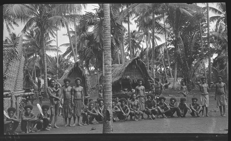Group in a village, men on left hold cricket bats