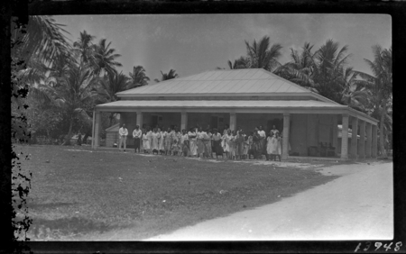 Men, women and children standing in front of building