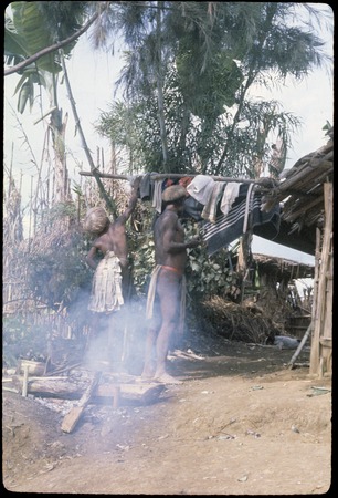 Akis (left) hangs up clothing and fabrics which he has purchased on a trip to Madang