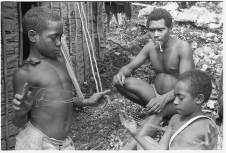 Laete&#39;eboo and his sons playing with lalefui&#39;olanga string figures in front of the men&#39;s house.