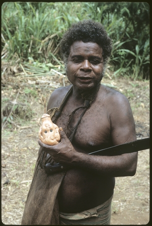 Portrait of a man, Batalamo, holding a doll head and a bush knife.