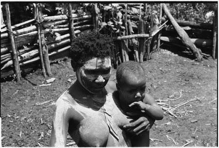 Bomagai: woman with face and body smeared with clay as a sign of mourning, she holds infant