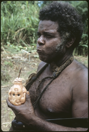 Portrait of man (Batalamo) holding a doll head.