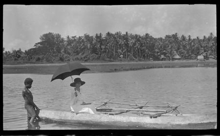 European woman in canoe, with man beside in water