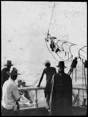 Group of men on ship, greeting two men on canoe