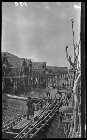 People in canoes, and houses on stilts over water at Gaile, also spelled Gaire, a Motu village in Central Province