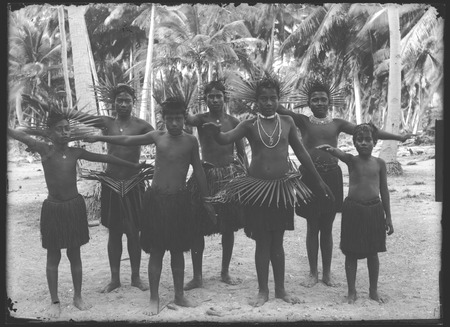 Boys posing in grass skirts, with waist and head piece