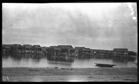 Houses on stilts over water, and canoe, at Gaile, a Motu village