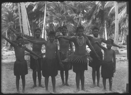 Boys posing in grass skirts, with waist and head piece