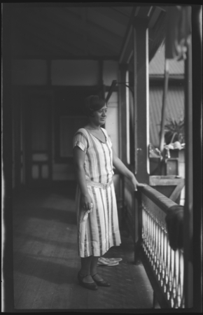 Portrait of woman standing on front porch of building