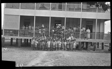 Group of children outside a building with Catholic missionaries; probably an orphanage, or boarding school