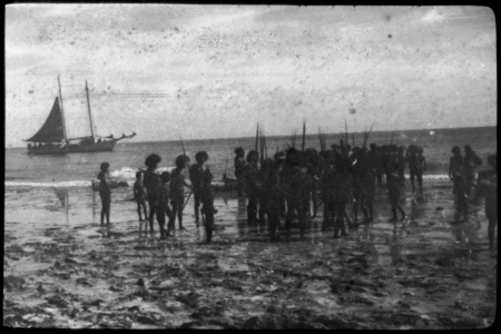 Group of people at the shore, with ship in the background