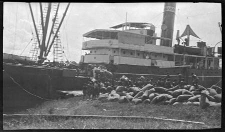 Men loading sacks of copra onto ship