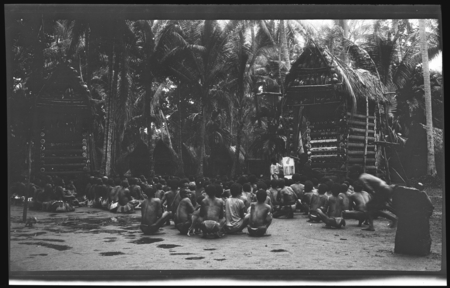 Hookworm lecture in front of yam houses, Trobriand Islands