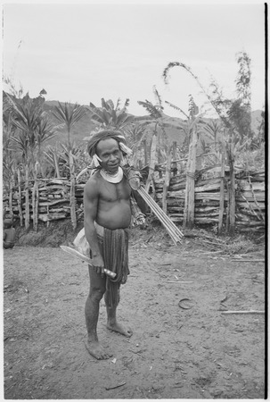 Man wears hornbill ornament, kina shell pendant, carries arrows and machete