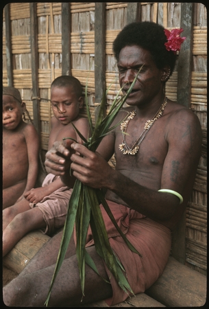 Man performing aringa divination as children look on.