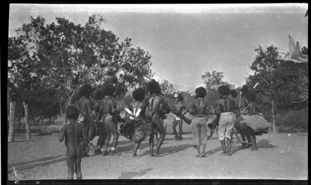 Motu men in circle, dancing anf playing kundu drums near a dubu platform