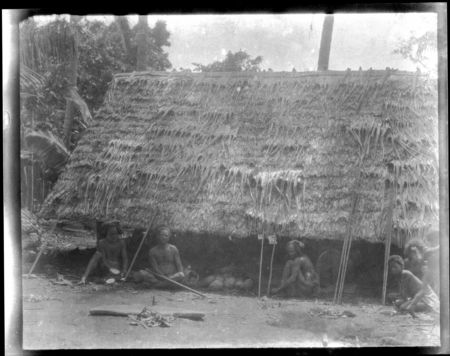 Several men sitting beside village dwelling