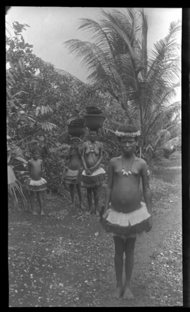 Trobriand Islands girls on path, carrying baskets on head