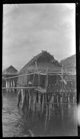 Children sitting on porch of stilted house over water at Gaile, a Motu village