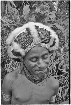 Man in headdress with marsupial fur, strands of shells and insects