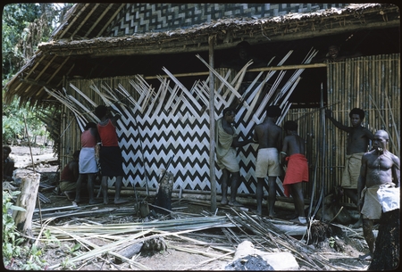 Men plaiting a wall of a house.