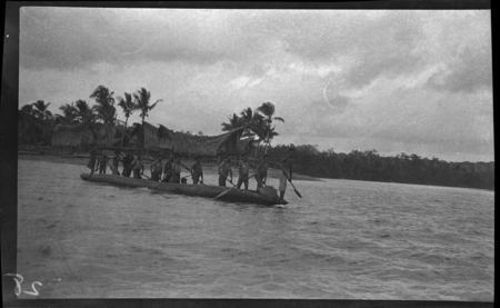 Men paddle canoe in front of Vaimuru (Baimuru)
