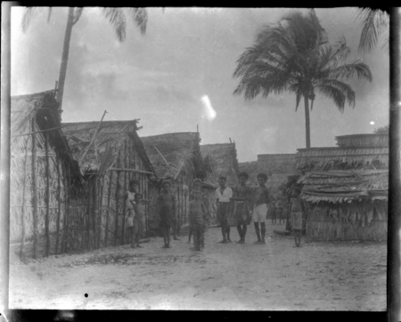 Men and children posing beside village dwellings