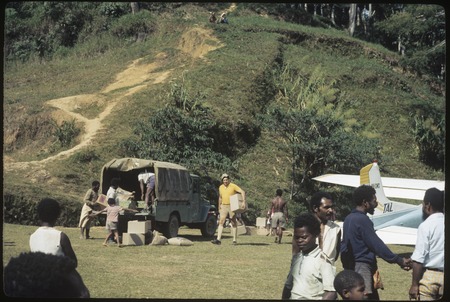 Government patrol officer, Jack Edwards, and others load boxes onto truck at Tabibuga airstrip