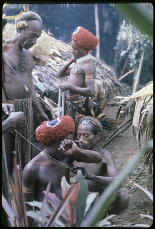 Pig festival, wig ritual: Mer puts kuri beads on Keap, who wears a red wig, Mak watches