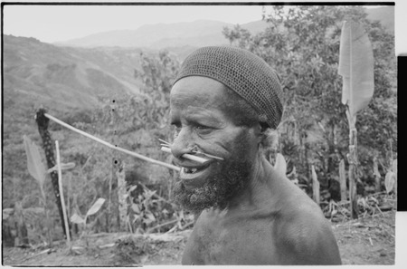 Older man with pierced nose, wears a cap netted from plant fibers