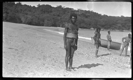 Men standing on shore, officers and boat in background at Malua Bay, Malekula