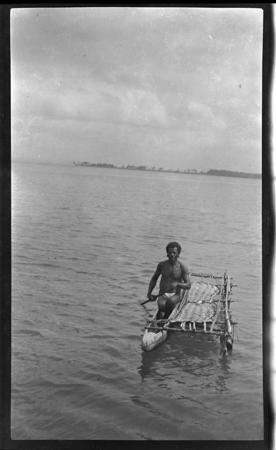 Man paddling a small outrigger canoe at Wamea Island, also Dum Dum Island, in Milne Bay