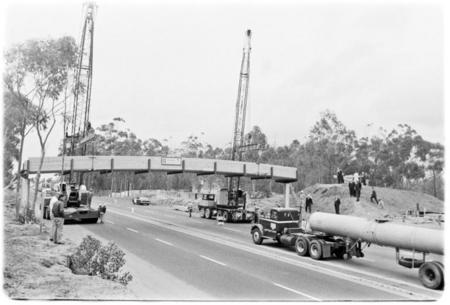 Pedestrian footbridge over U.S. Highway 101 hoisted into place by two cranes