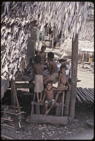 Woman and smiling children gathered on a house veranda, Tukwaukwa village, Kiriwina
