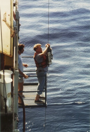 Harmon Craig attaching an instrument to a cable onboard a research ship, n.d.