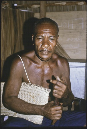Kunagesa, a prominent man in Kula exchanges, holding basket and mashing betel nut with mortar and pestle