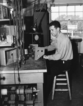 Man working at bench with electronics equipment, University of California Division of War Research
