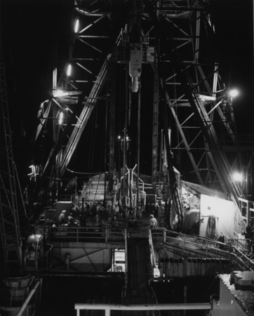 The D/V Glomar Challenger (ship) rig floor as it was seen at night during drilling for the Deep Sea Drilling Project. 1979.