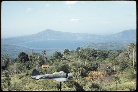 Rabaul Coastwatcher&#39;s Memorial, World War 2-era airplane displayed, caldera and volcanic peaks in background