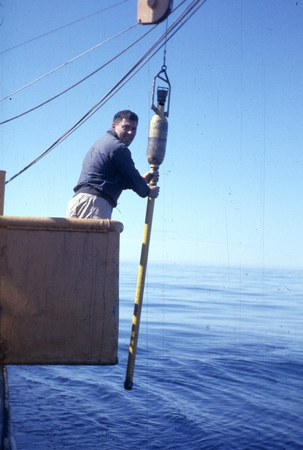 Coring device being lowered in the water by a man on board the R/V Spencer F. Baird (ship), during the Mukluk Expedition (...